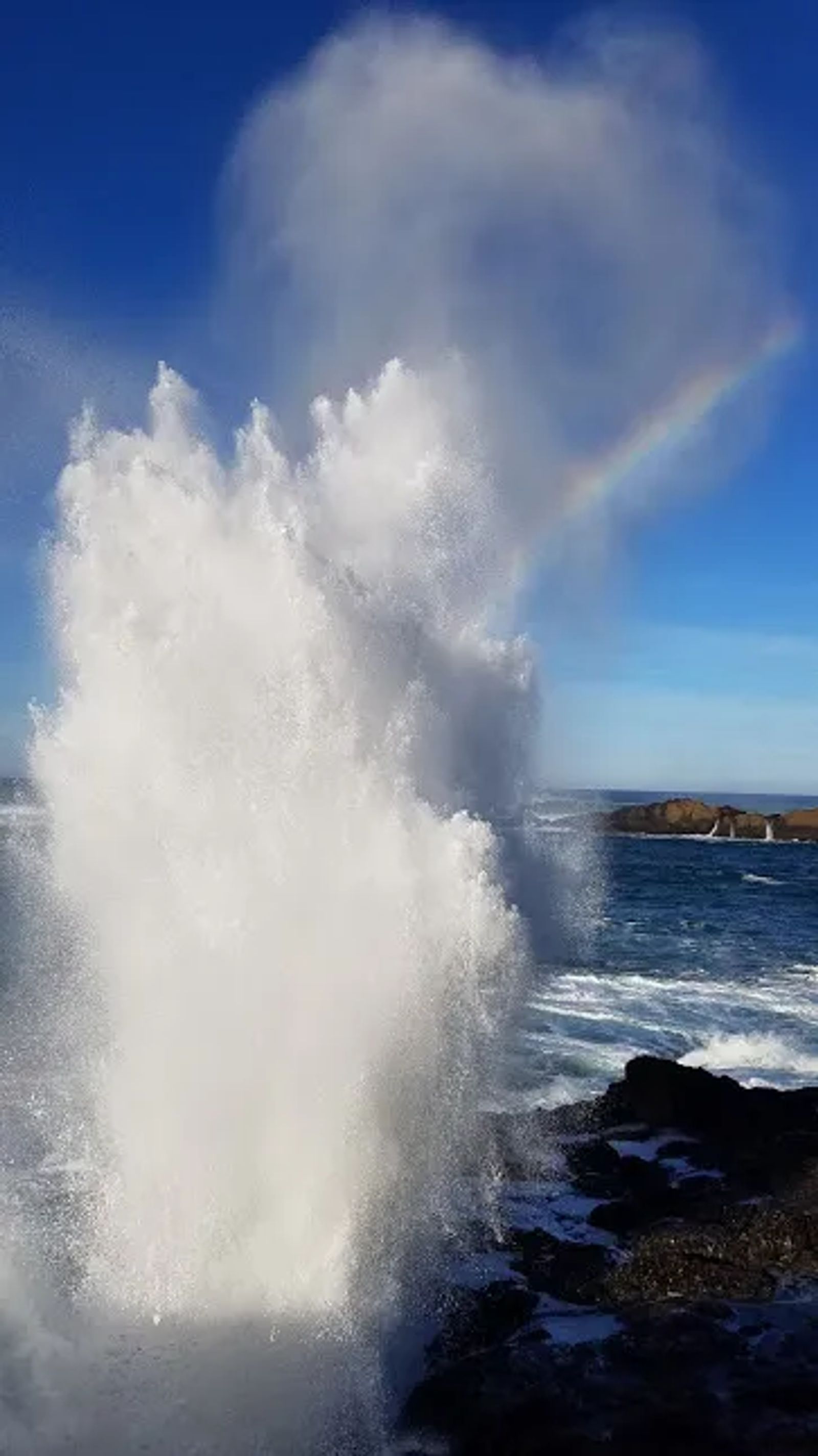 Photo of a water spout and rainbow from the surf in Depoe Bay, Oregon