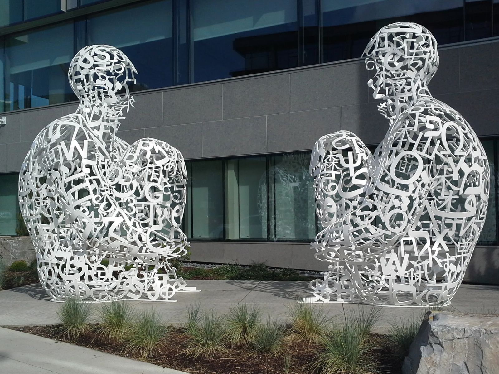 Photo of two 12 foot tall, white, stainless steel sculptures sitting face-to-face, in Seattle, Washington